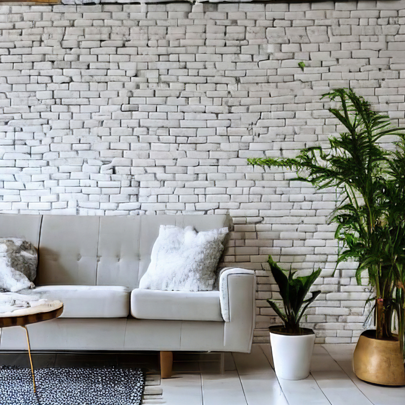 A living room with a wall of bricks painted in white and with few plants